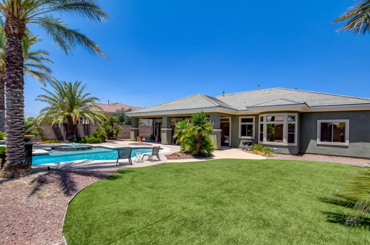 Backyard lawn and pool with the rear of the home