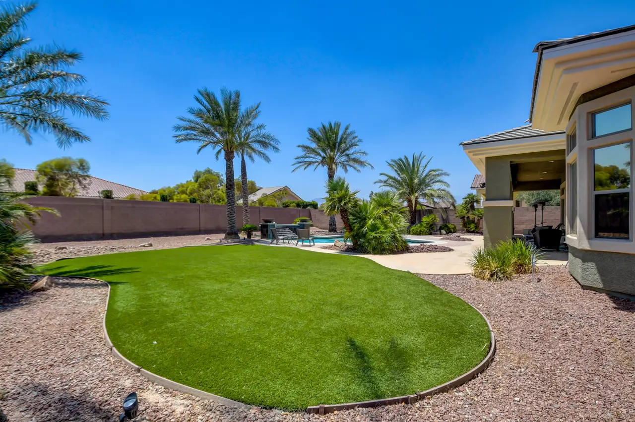 Turf lawn and palms inside the block-walled backyard