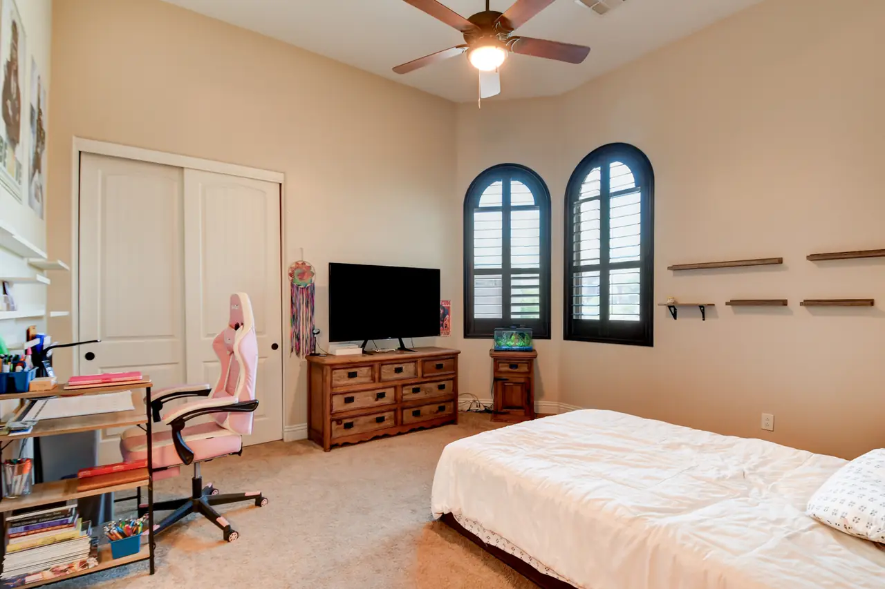 Bedroom with arched shuttered windows and a ceiling fan