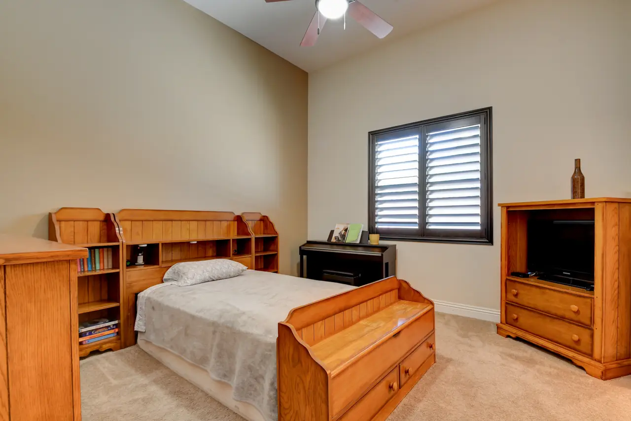 Bedroom with shuttered window and wood furniture