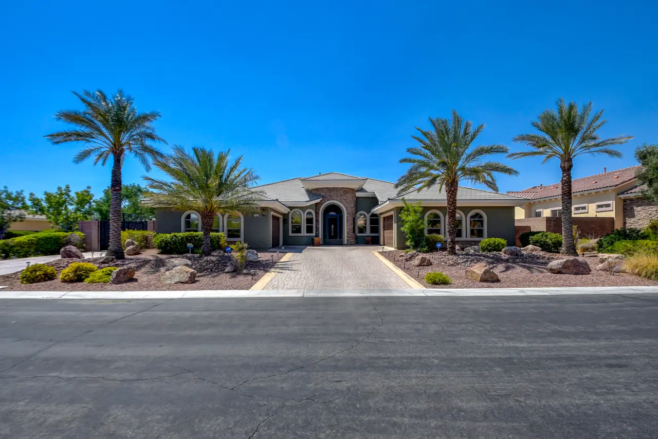 The home on its corner lot seen from the street, framed by tall palms