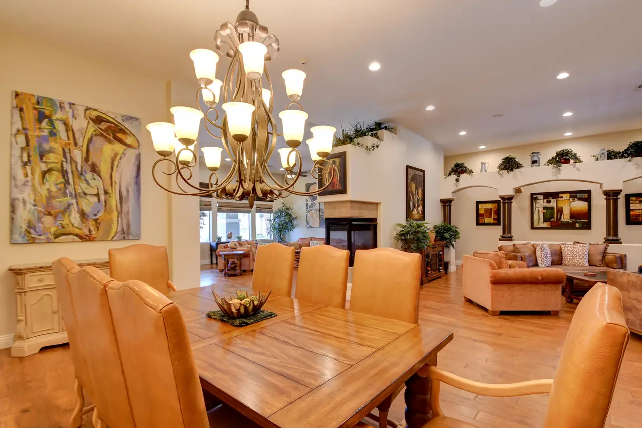Dining room under a tiered chandelier with hardwood floors and the living room beyond