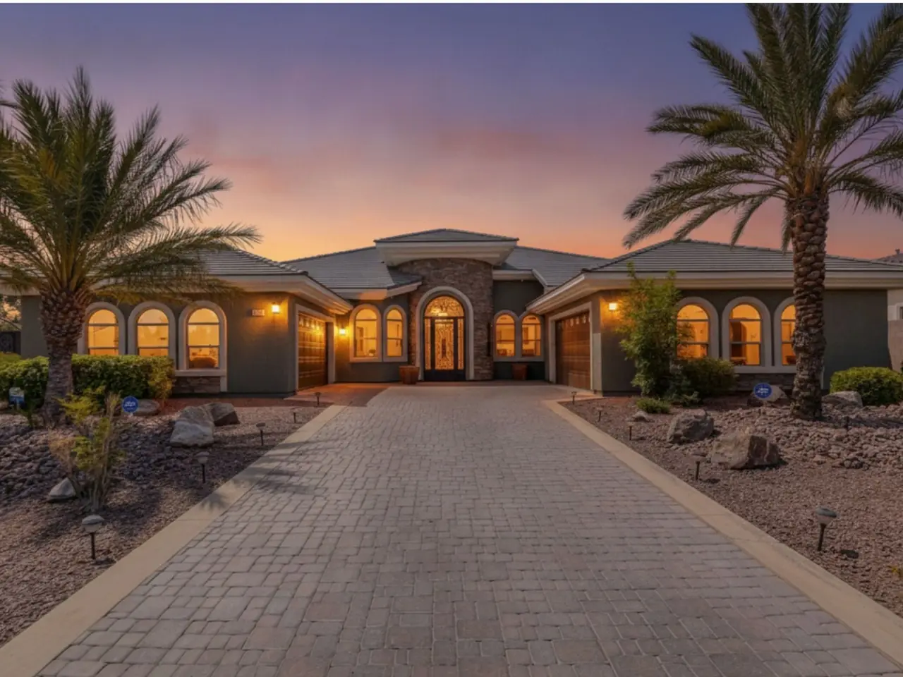 8465 Picket Ridge Ct at twilight, a single-story home with lit windows behind palms and a long paver driveway