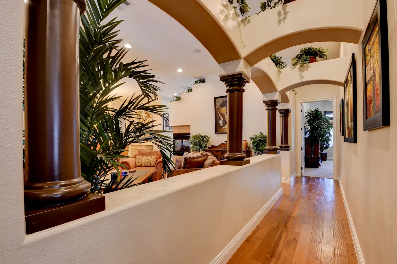 Hallway with arches and columns over a half wall with planters