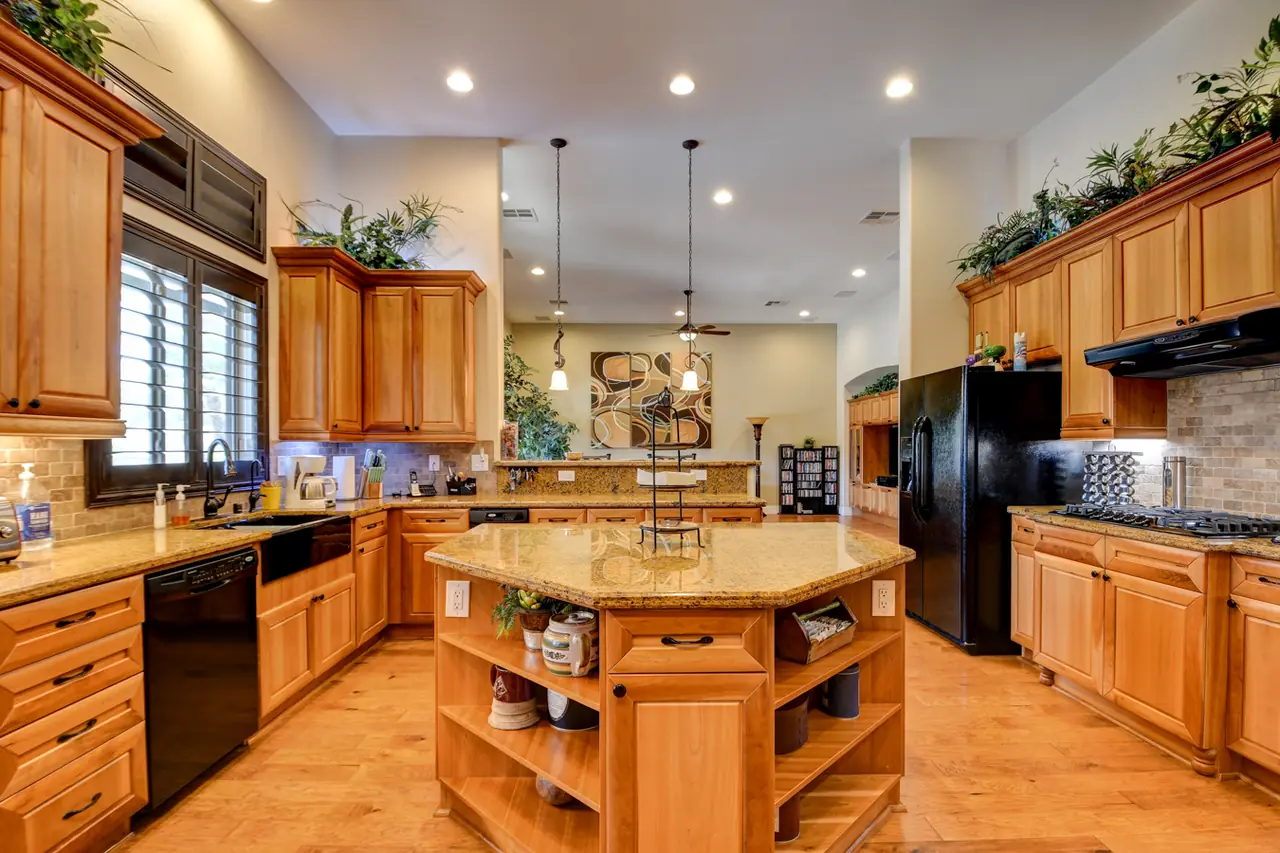 Kitchen with granite counters, an island with open shelving and wood cabinets