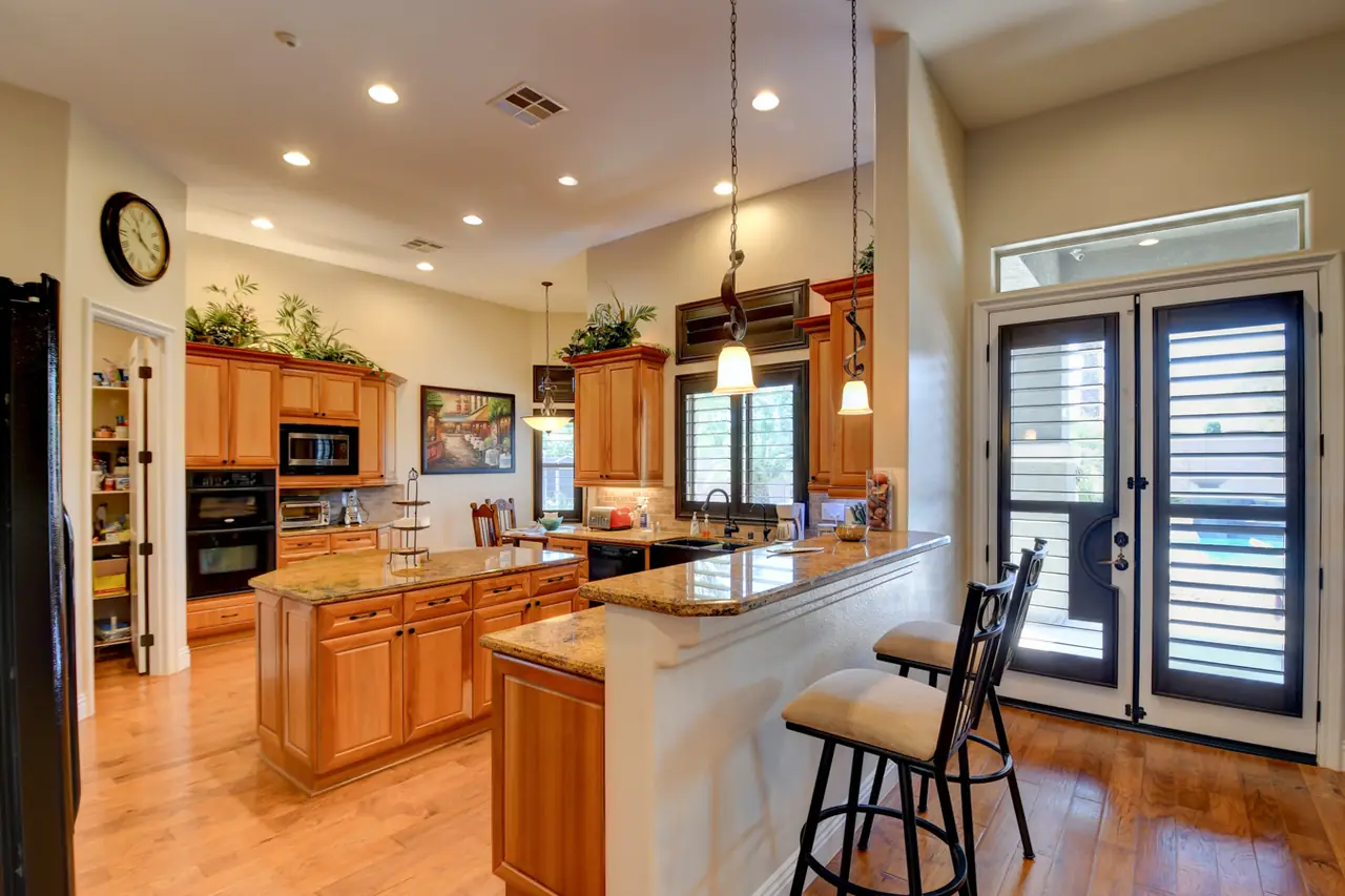 Kitchen with a granite island, pendant lights and French doors to the backyard