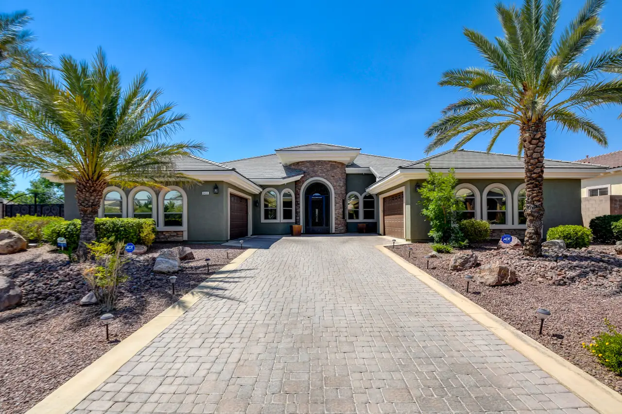 Long paver driveway leading to the arched entry between palms and desert landscaping