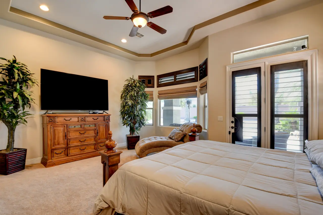 Primary bedroom with shuttered windows and French doors to the backyard