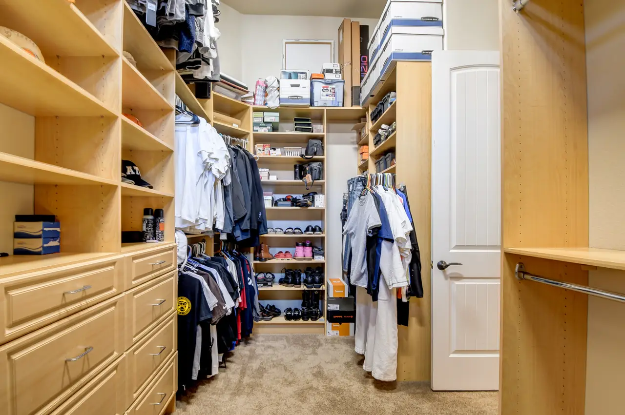 Primary walk-in closet with custom built-in shelving and drawers